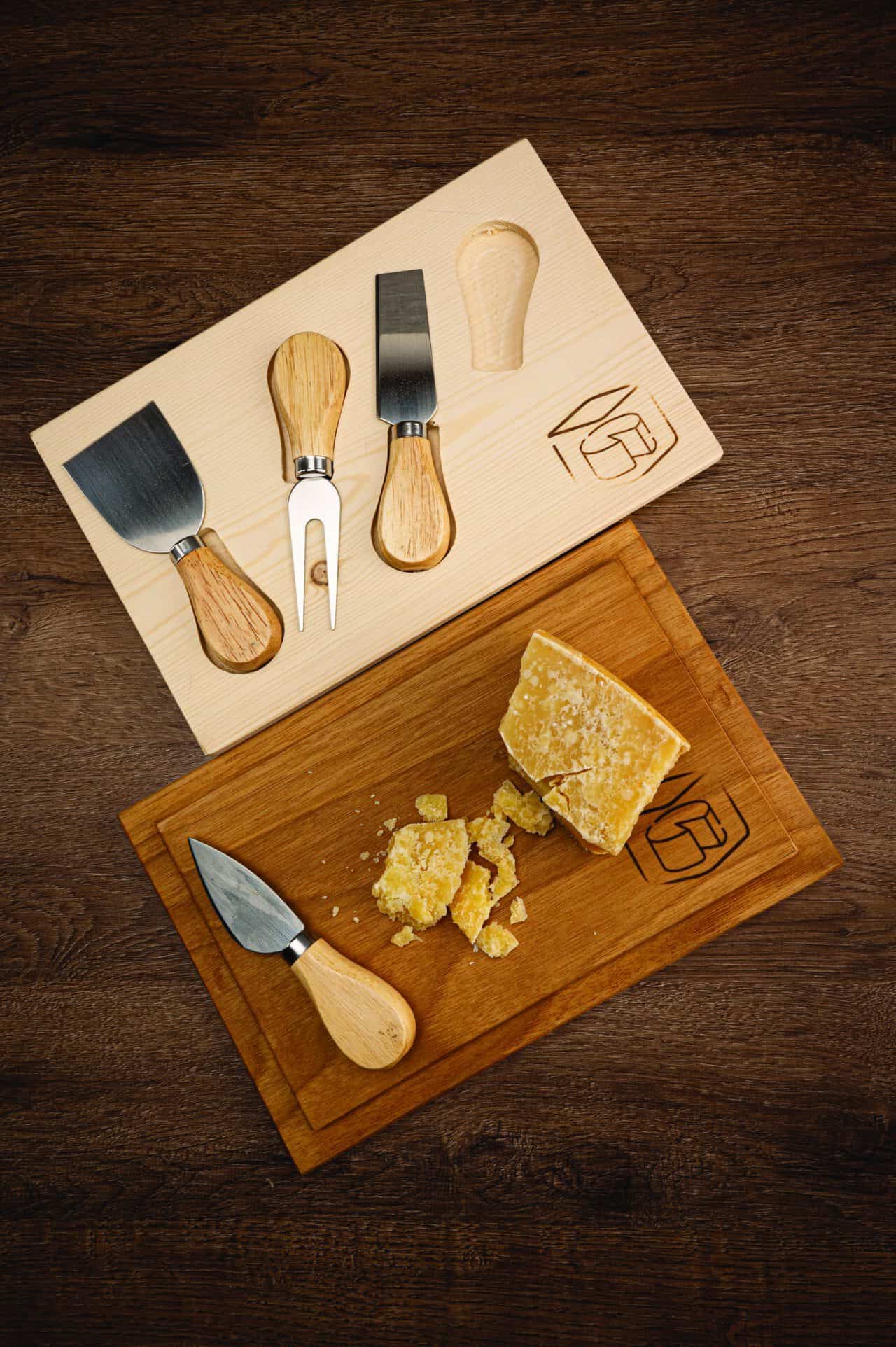 Utensili da cucina con manici in legno e spatole, presentati su un tagliere di legno con formaggio e.