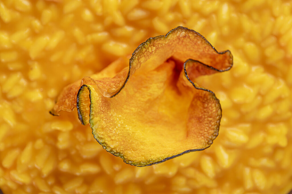 Fetta di zucca croccante su sfondo di polpa di zucca gialla.